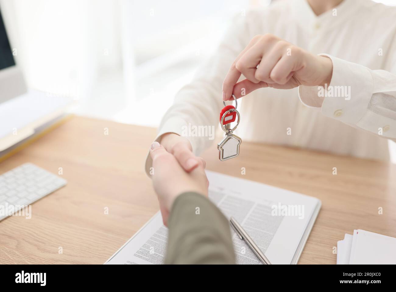 Real estate manager shaking hands with client and giving keys to new ...