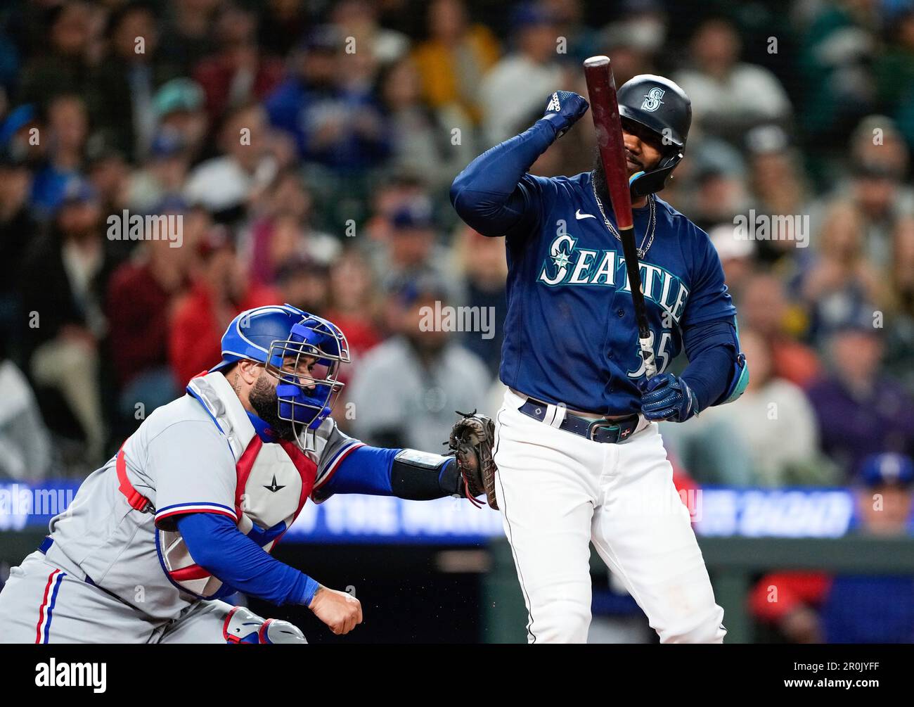 Seattle Mariners' Teoscar Hernandez, right, motions towards his bat
