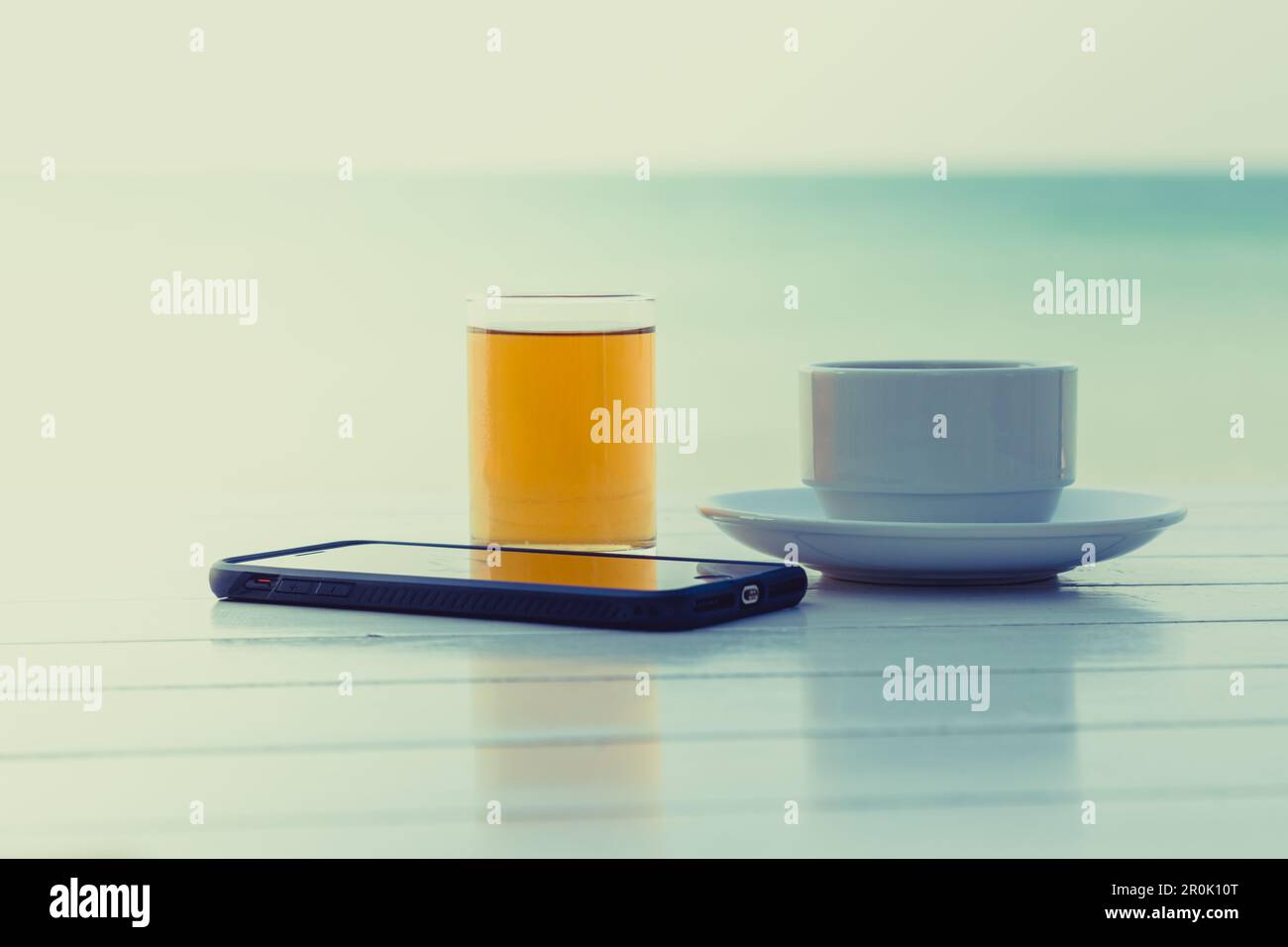 Tea coffee with smart phone on the white wooden table at the beach background Stock Photo