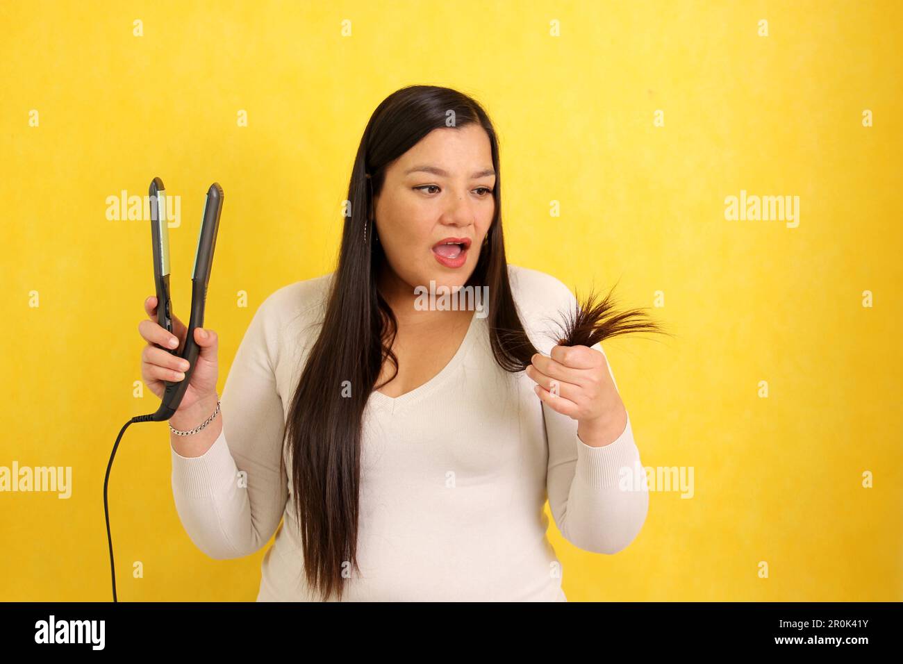 Adult Latina woman with very long straight hair combs her hair with a