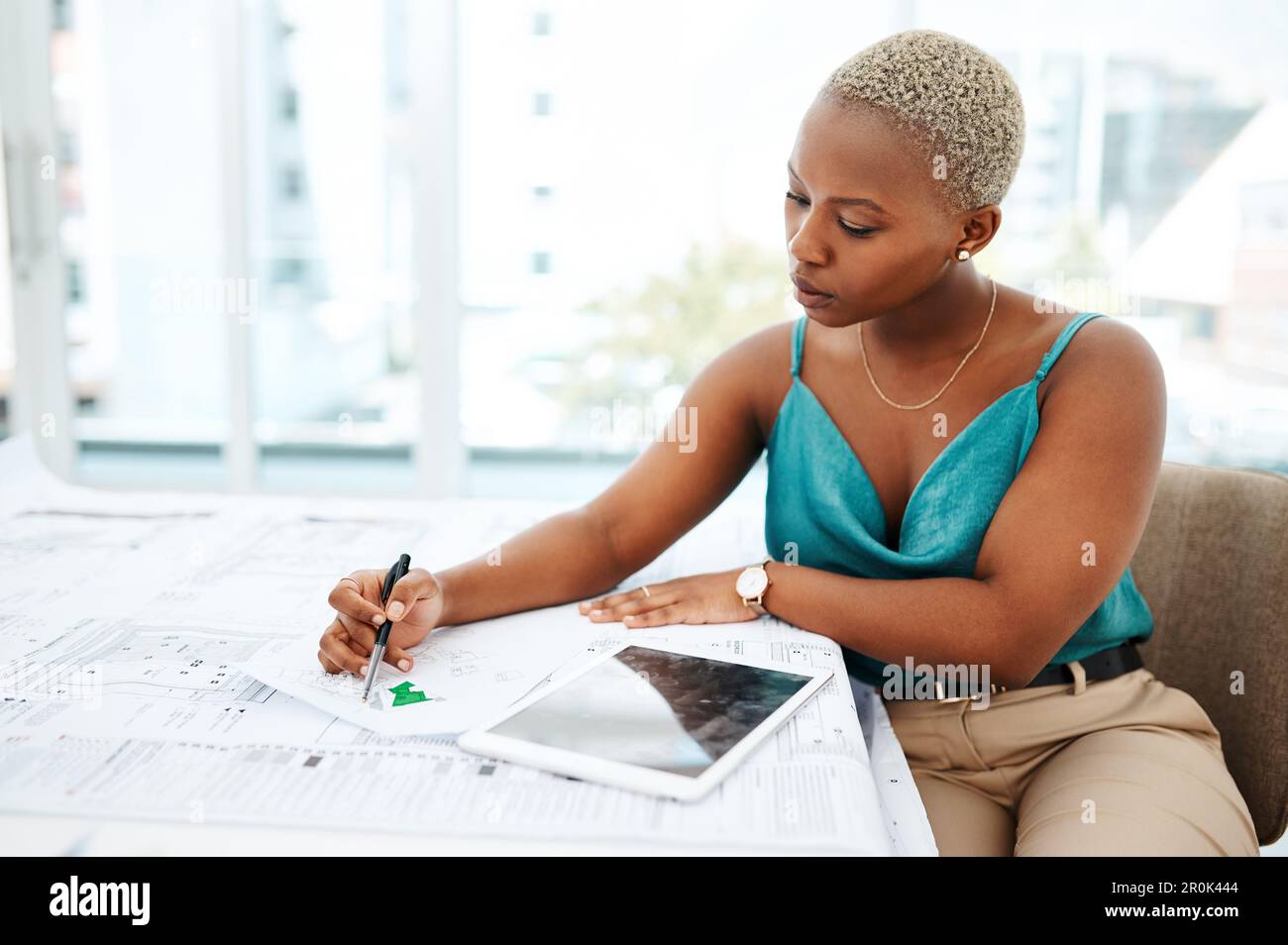 Giving every design all shes got. a young woman going over blueprints ...