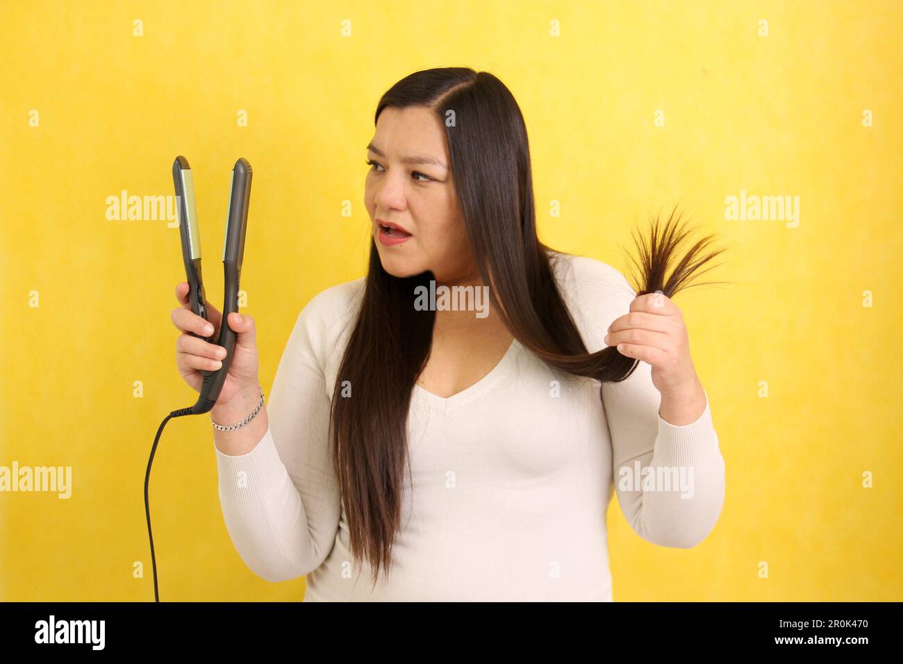 Adult Latina woman with very long straight hair combs her hair with a