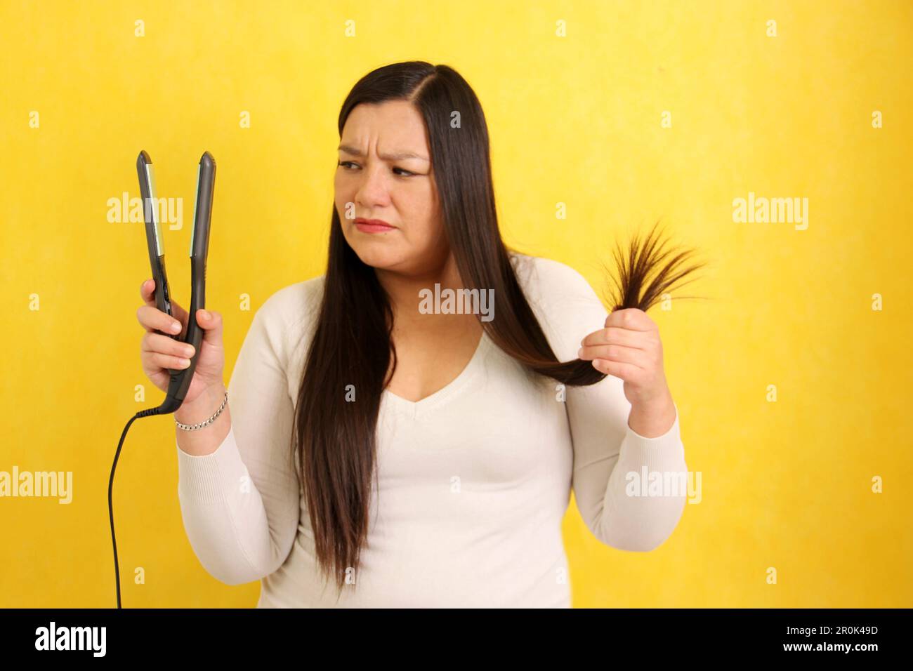 Adult Latina woman with very long straight hair combs her hair with a