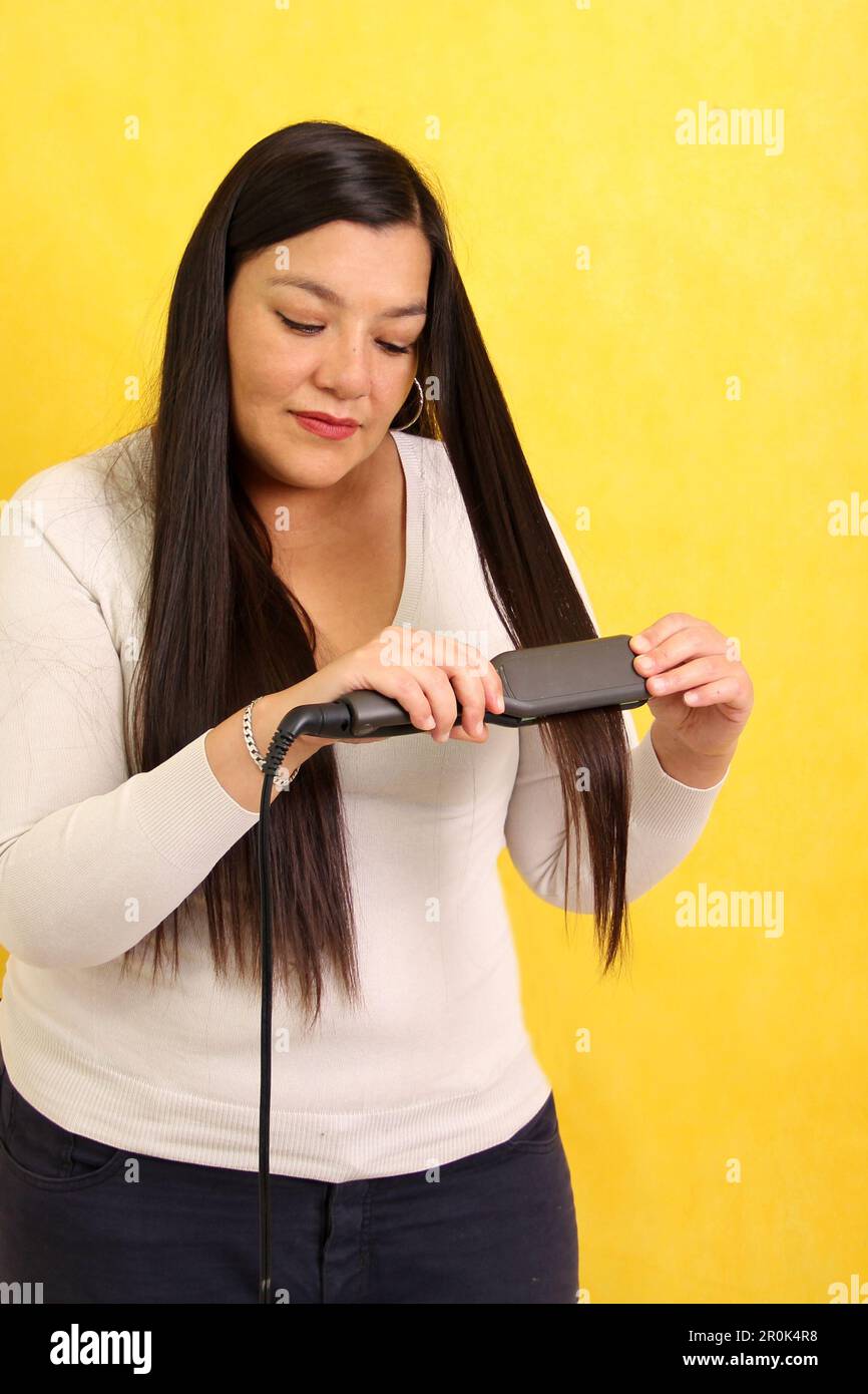 Adult Latina woman with very long straight hair combs her hair with a