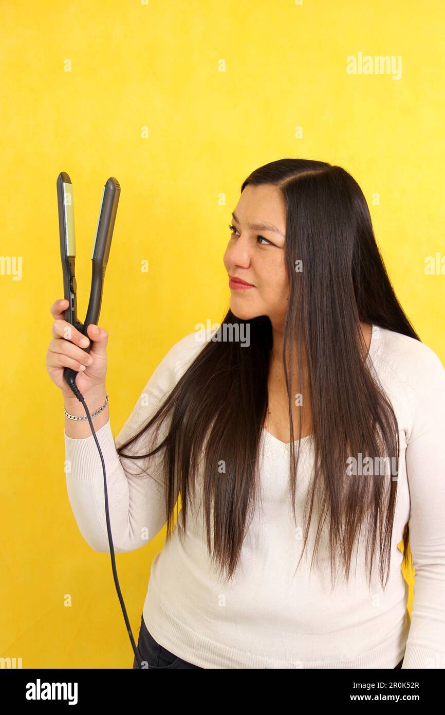 Adult Latina woman with very long straight hair combs her hair with a