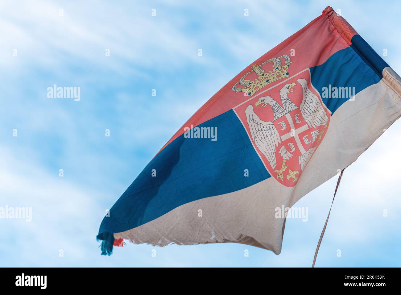 Torn and weathered flag of Serbia on a post waving in wind, selective focus Stock Photo