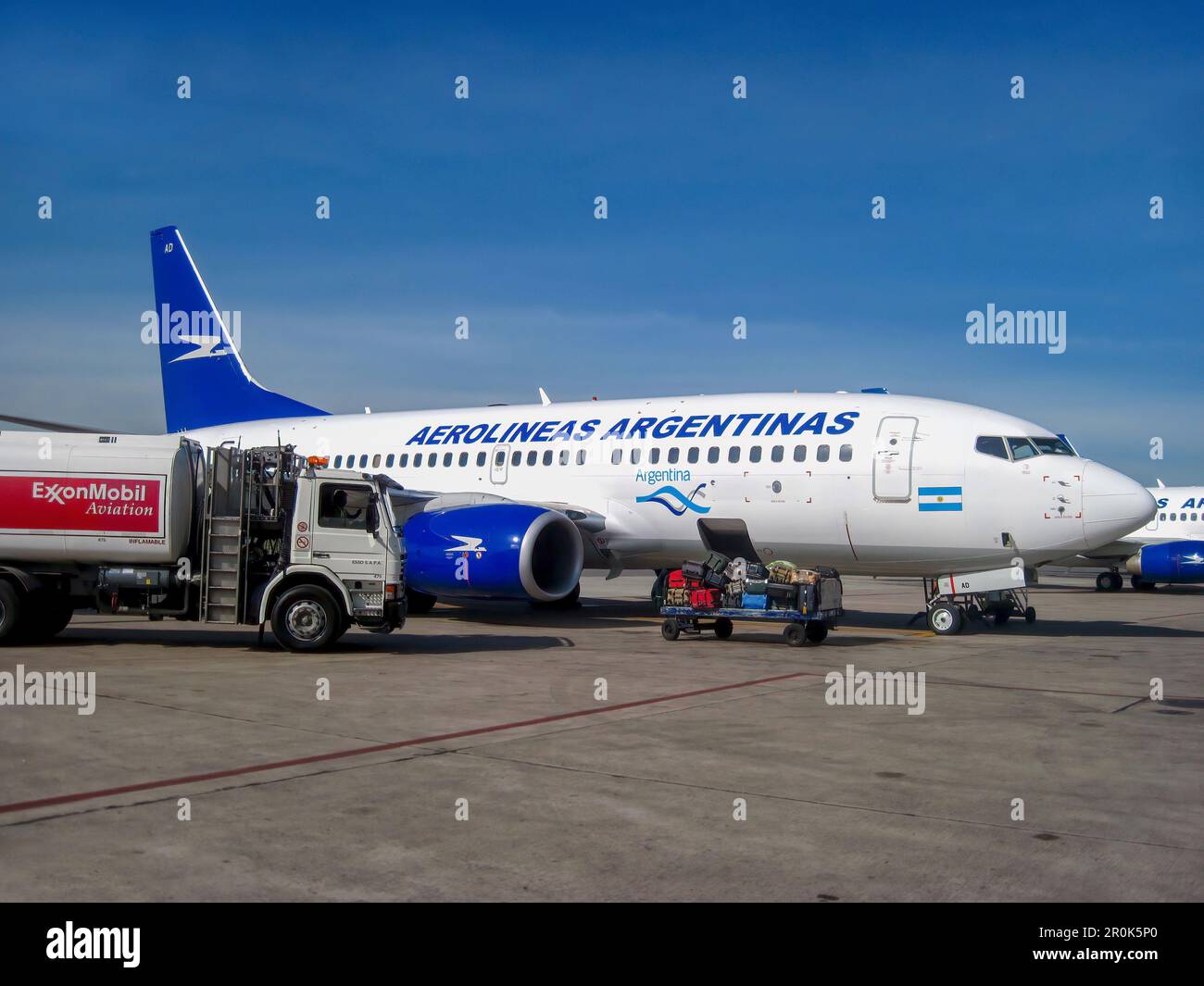 Buenos Aires, Argentina - Nov 19, 2010. An Aerolineas Argentinas passenger jet on the airport tarmac next to an ExxonMobil fuel truck and luggage cart Stock Photo