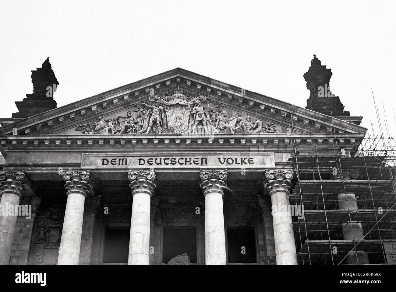 Original-Bildunterschrift: 'Dem deutschen Volke' - Die Gerüste am kriegszerstörten ehemaligen Reichstagsgebäude in Berlin fallen. Die Renovierungsarbeiten gehen mit Riesenschritten ihrer Fertigstellung entgegen. Über 250 Arbeiter sind beim Wiederaufbau des Gebäudes beschäftigt. Die West- und Südfassade strahlen bereits im früheren Glanz, hier die renovierten Reliefs über dem Haupteingang des 1884 bis 1894 von Paul Wallot erbauten Reichstagsgebäudes, Berlin, Deutschland 1958. Stock Photo