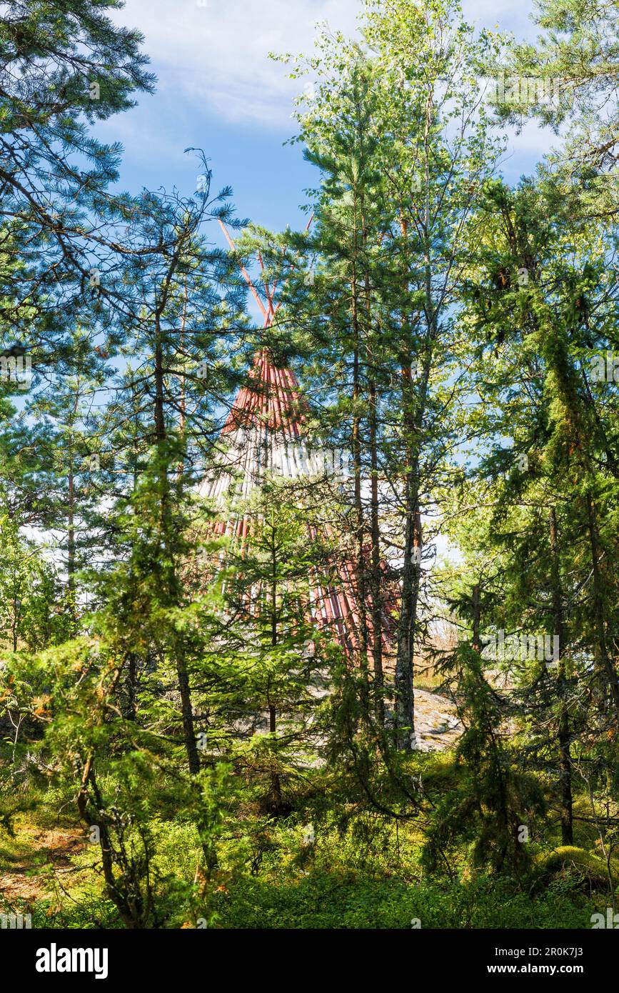 view through green needle trees to a red and white wooden tent, Oregrund, Uppsala, Sweden Stock Photo