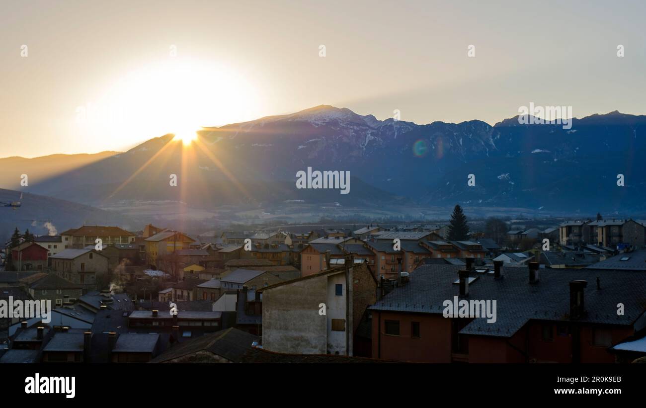 Sun flare shining through a mountain silhouette landscape on a rural village scenic Stock Photo