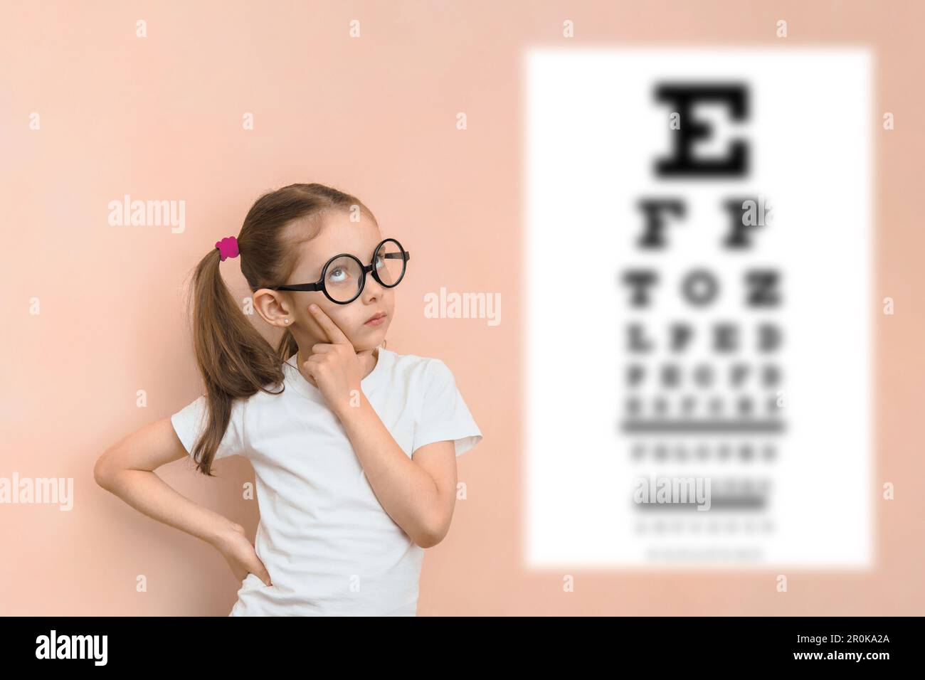 Thoughtful smart girl of elementary school age in diopter glasses