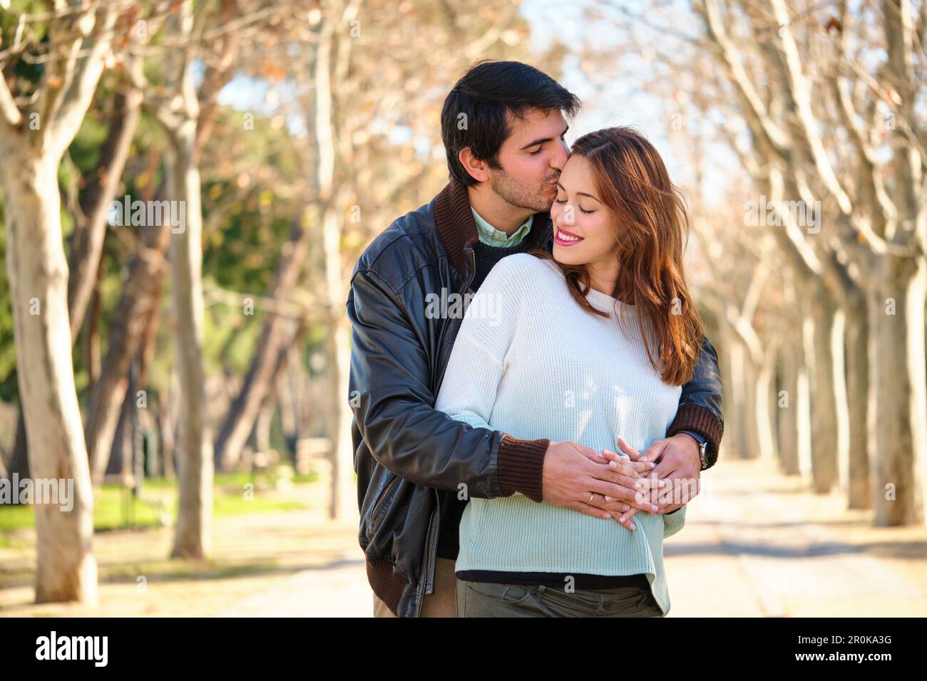 Man kissing his happy pregnant wife, couple embracing in a park Stock ...