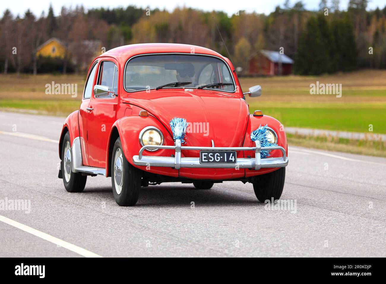 Red Volkswagen Beetle, officially Volkswagen Type 1, driving along Highway 110 on May Day car cruising event. Salo, Finland. May 1, 2023. Stock Photo