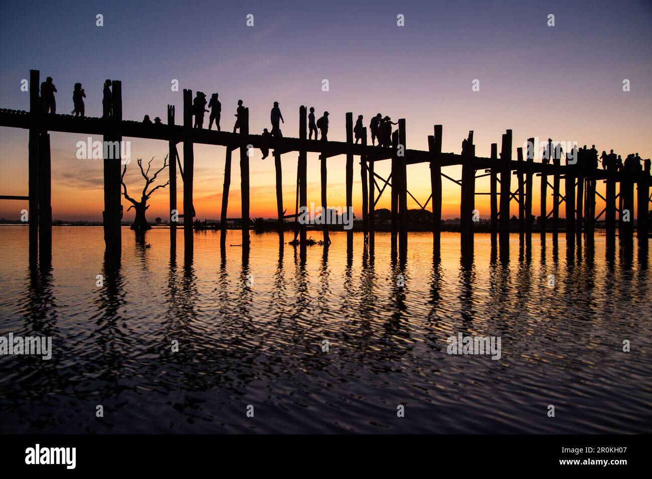 Silhouette of people walking along U Bein Bridge across Taungthaman ...