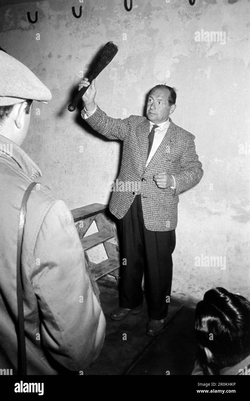 Ein Reiseleiter im Konzentrationslager Buchenwald mit einer Keule in der Hand, 1960. A tour guide at Buchenwald concentration camp with a club in his hand, 1960. Stock Photo