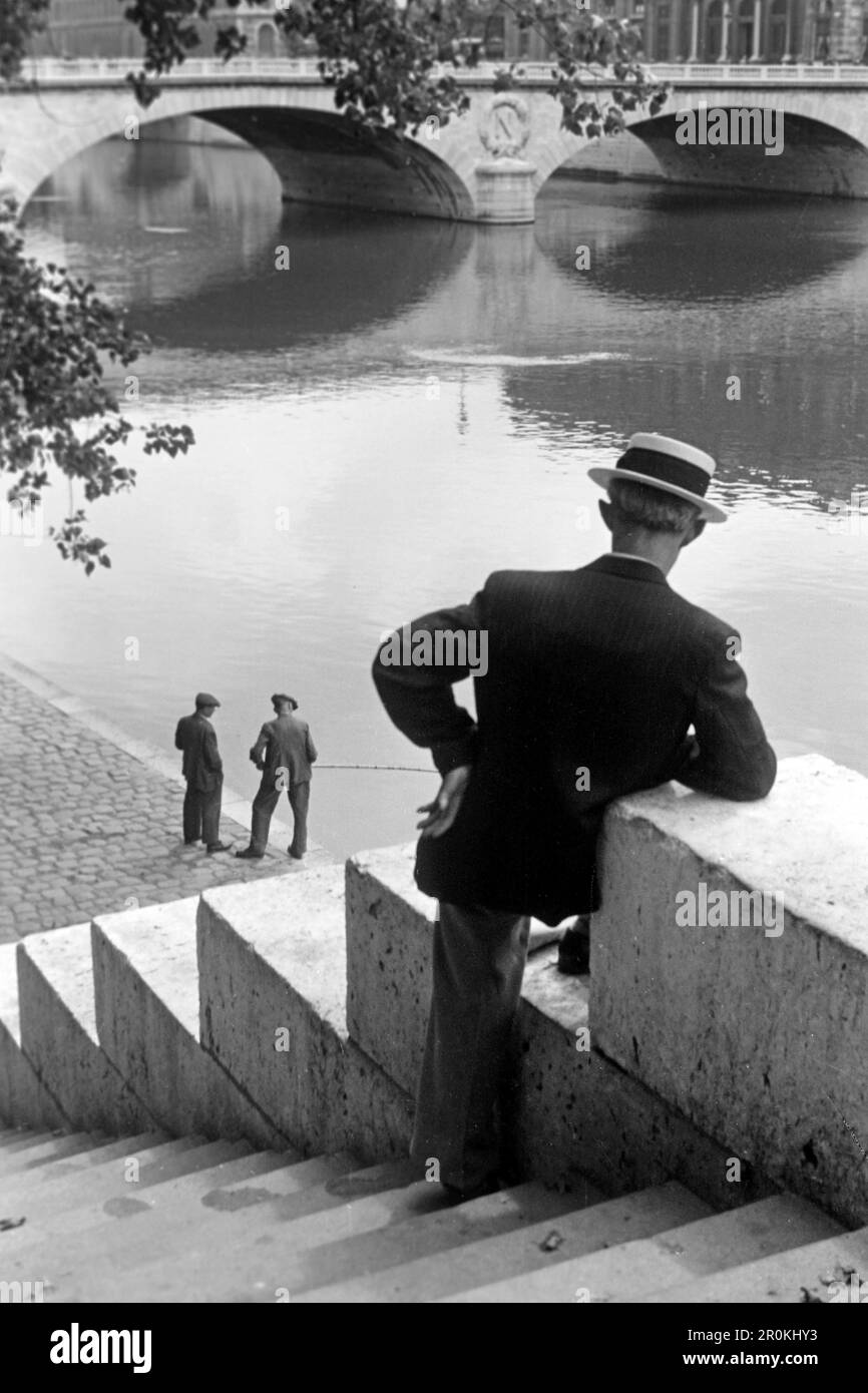 Herr betrachtet zwei Angler am Rand der Seine, der Pont Saint Michel im Hintergrund, Paris 1940. Gentleman looking at two anglers on the edge of the Seine, the Pont Saint Michel in the background, Paris 1940. Stock Photo