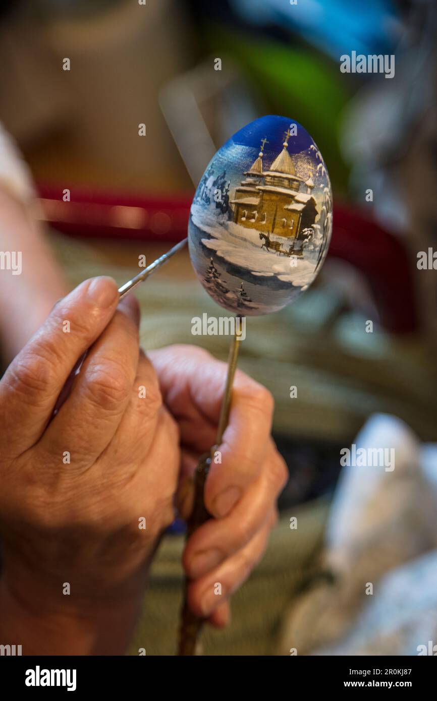 Detail of hand of woman painting souvenir Faberge-style egg at Mandrogi crafts village, Mandroga, Svir river, Russia Stock Photo