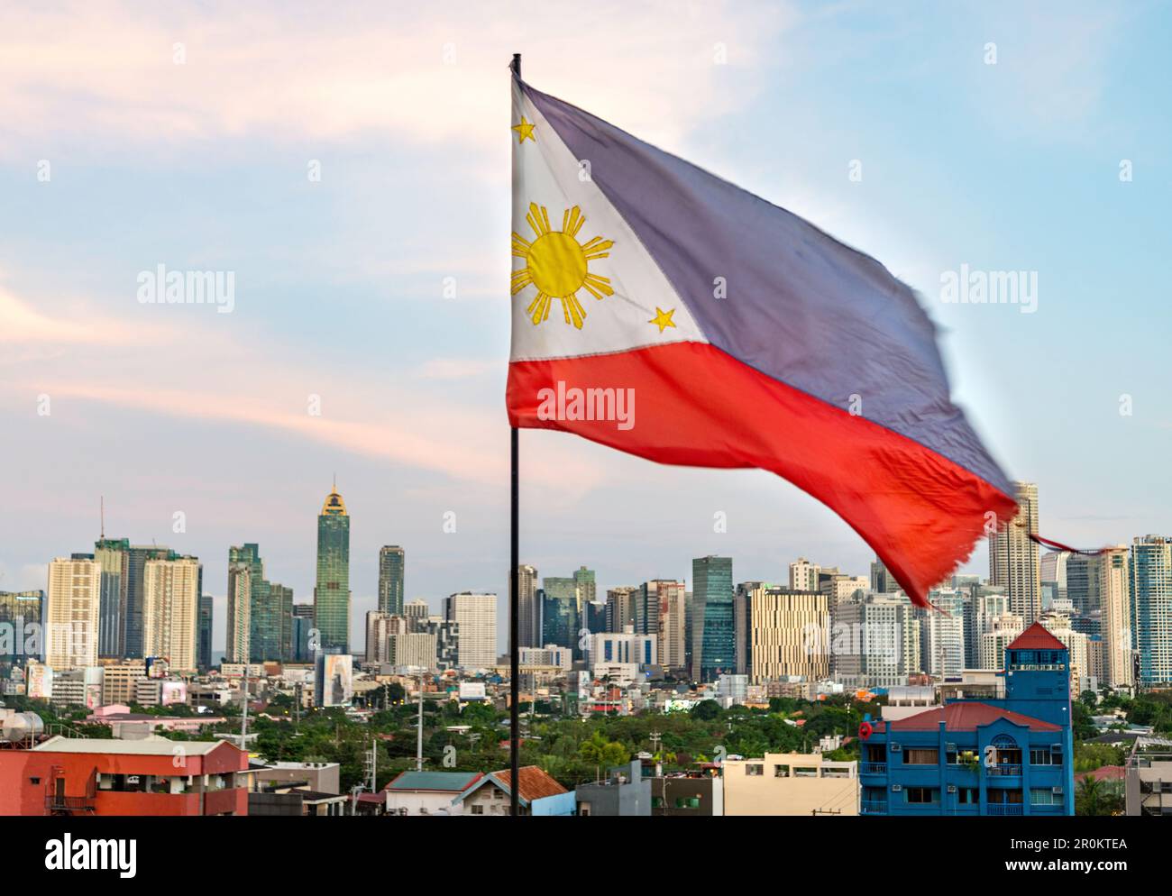 In the early evening afterglow of sunset,the red,blue and white Philippine flag flies,with it's golden sun and stars showing, in the warm breeze, on a Stock Photo