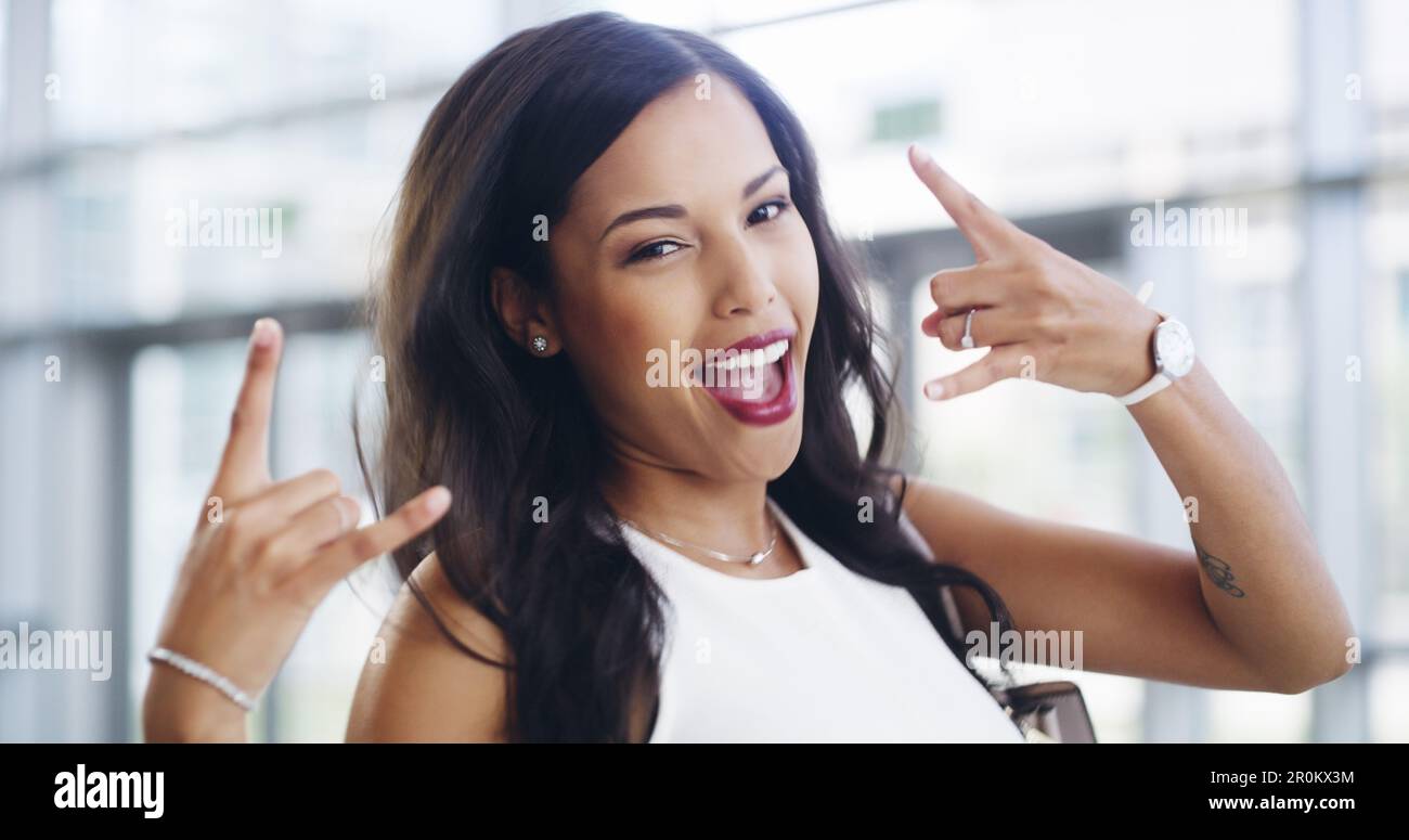 Keep rockin. a young businesswoman showing a shaka hand sign while walking through a modern office. Stock Photo