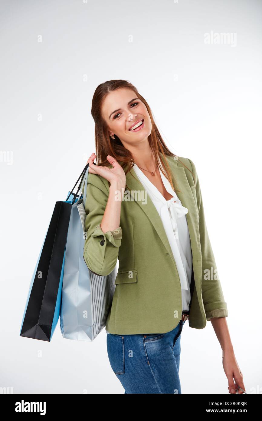 You worked hard, time to treat yourself. Studio portrait of a happy young woman carrying shopping bags against a grey background. Stock Photo