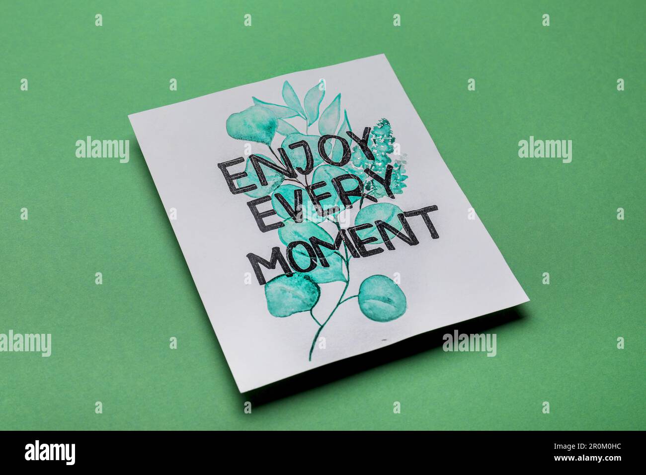 Card with phrase Enjoy Every Moment on green background Stock Photo