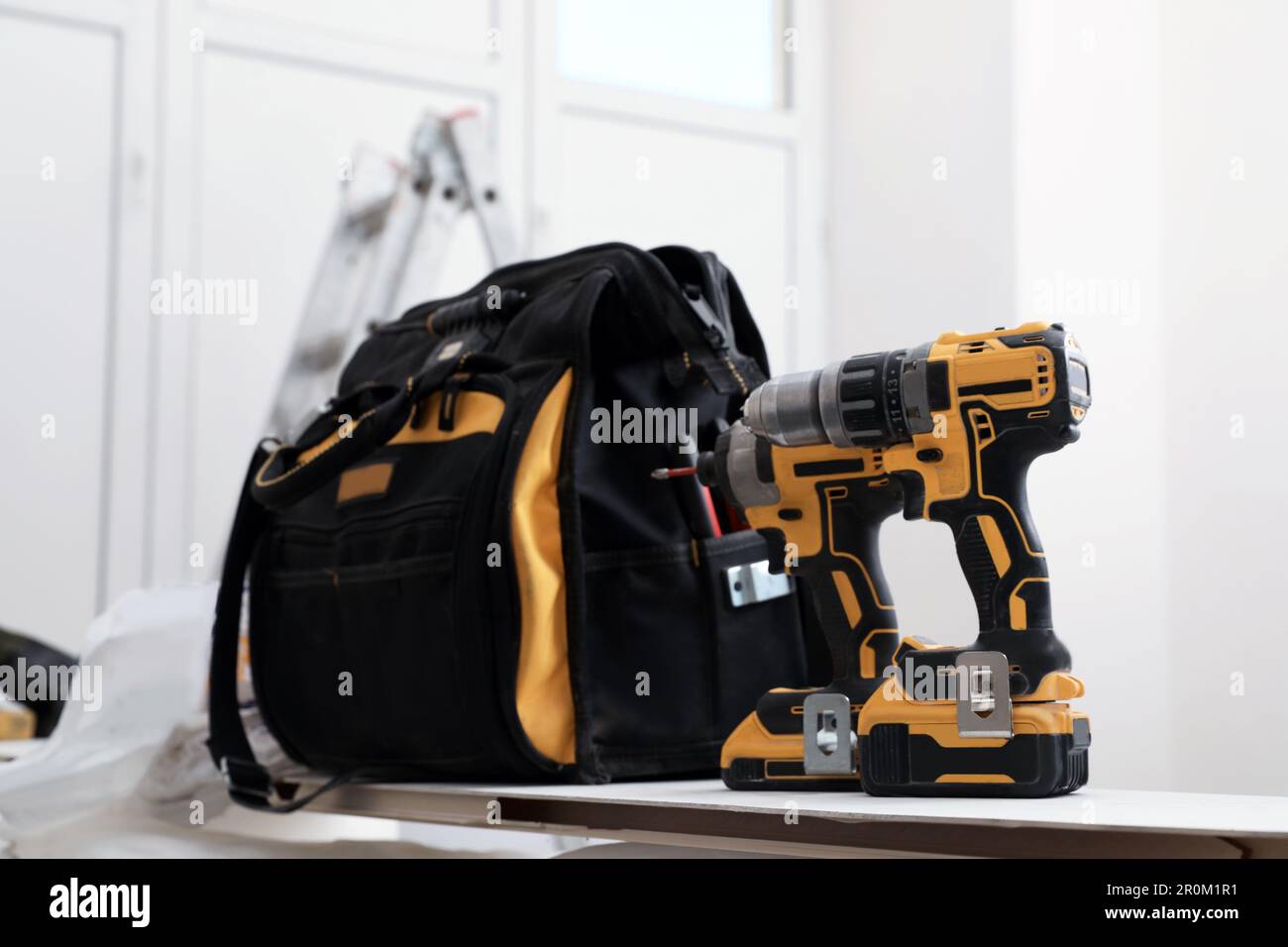 Men's hands in work gloves with a yellow screwdriver screw the roofing  sheet to the roof of a country house. Cordless drill Stock Photo - Alamy