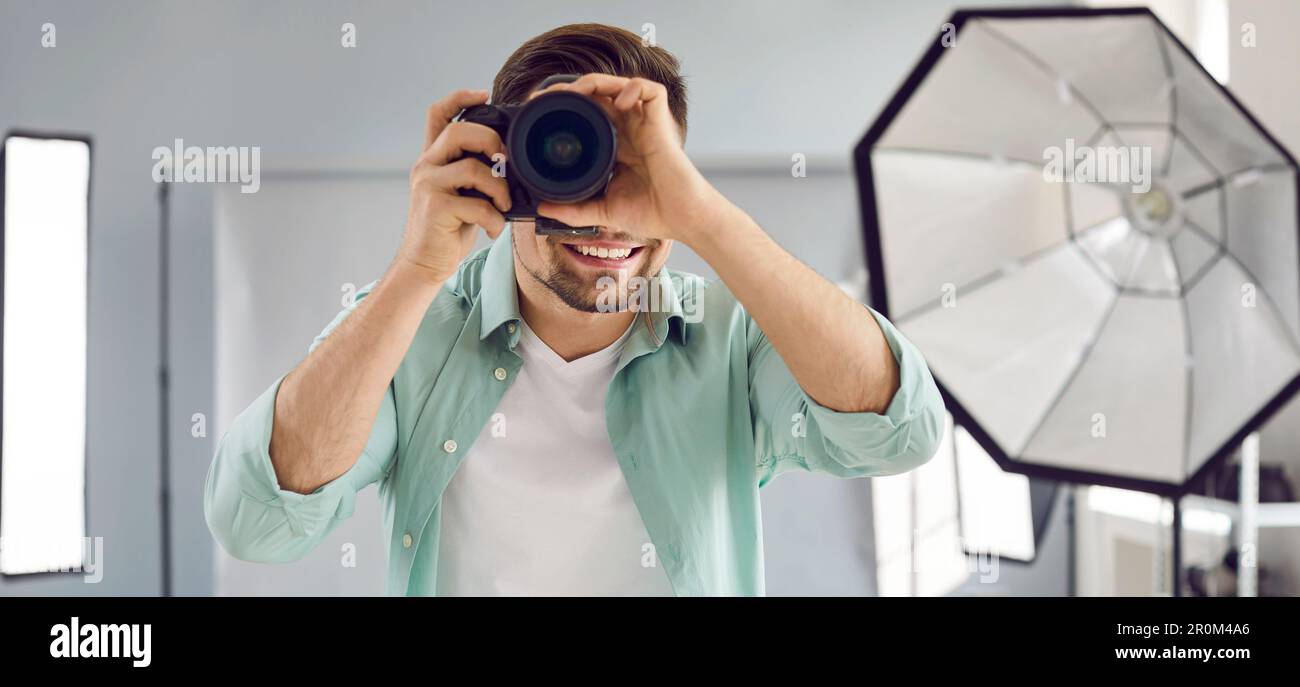 Young male photographer using professional camera in studio Stock Photo