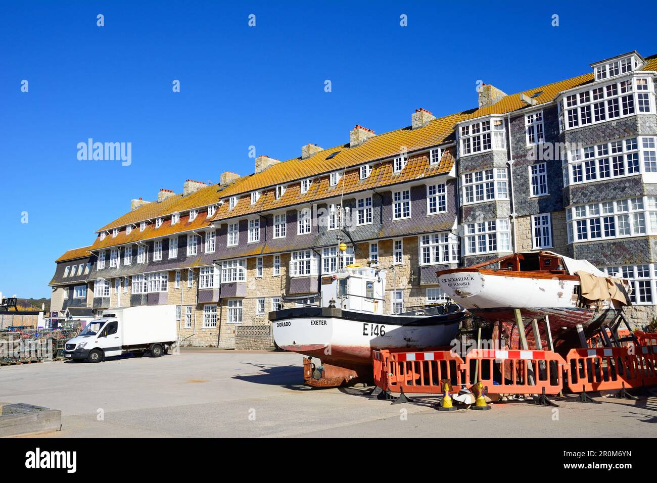 Boats in dry dock on the harbourside with apartments to the rear, West Bay, Dorset, UK, Europe. Stock Photo