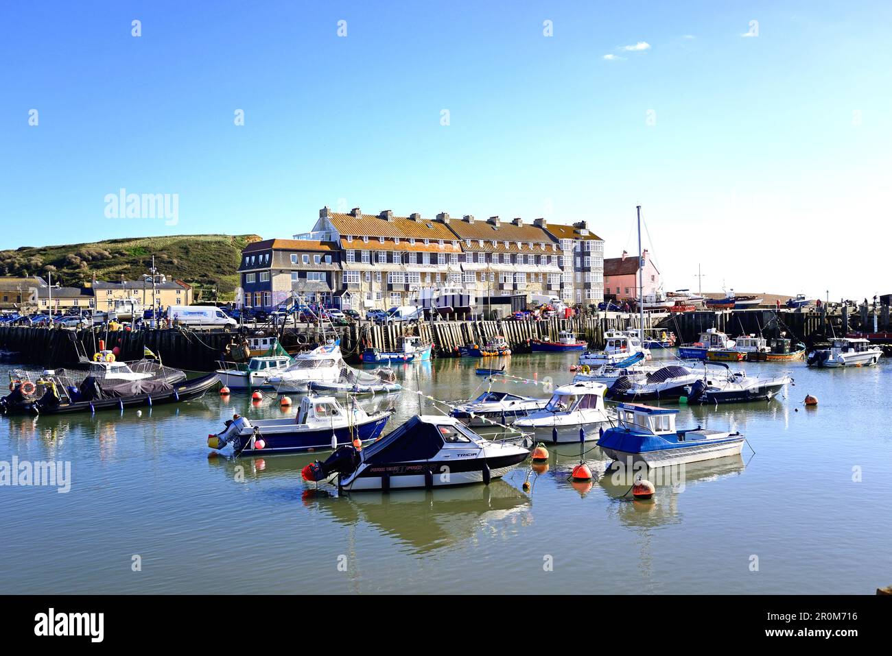 Fishing boats moored in the harbour with apartments to the rear, West Bay, Dorset, UK, Europe. Stock Photo