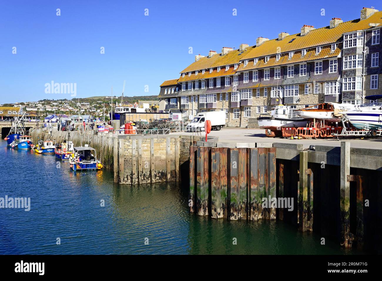 Fishing boats moored in the harbour with apartments and town buildings to the rear, West Bay, Dorset, UK, Europe. Stock Photo
