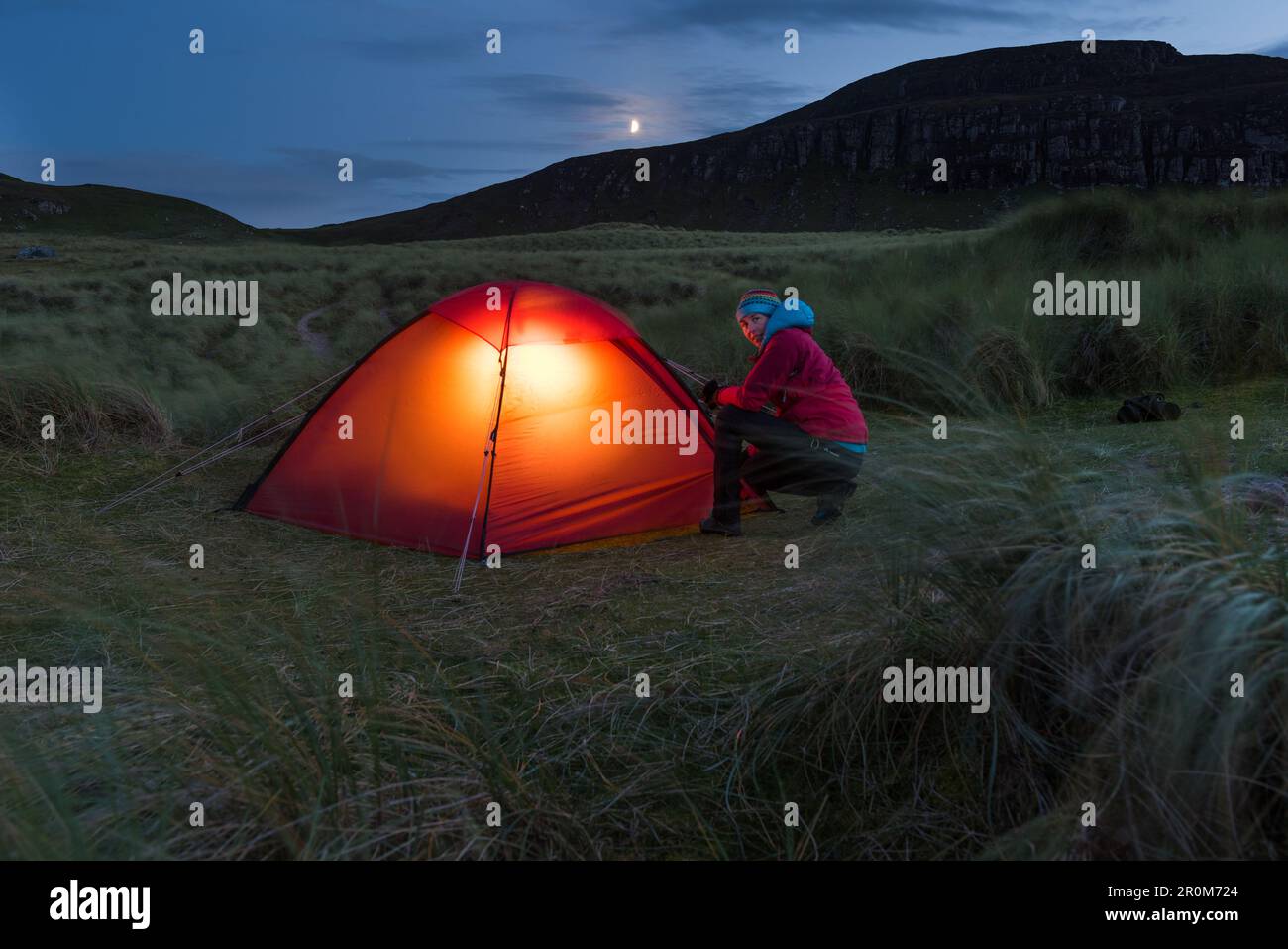 A woman in front of lit tent, Sandwood Bay, Highlands, Scotland, UK Stock Photo