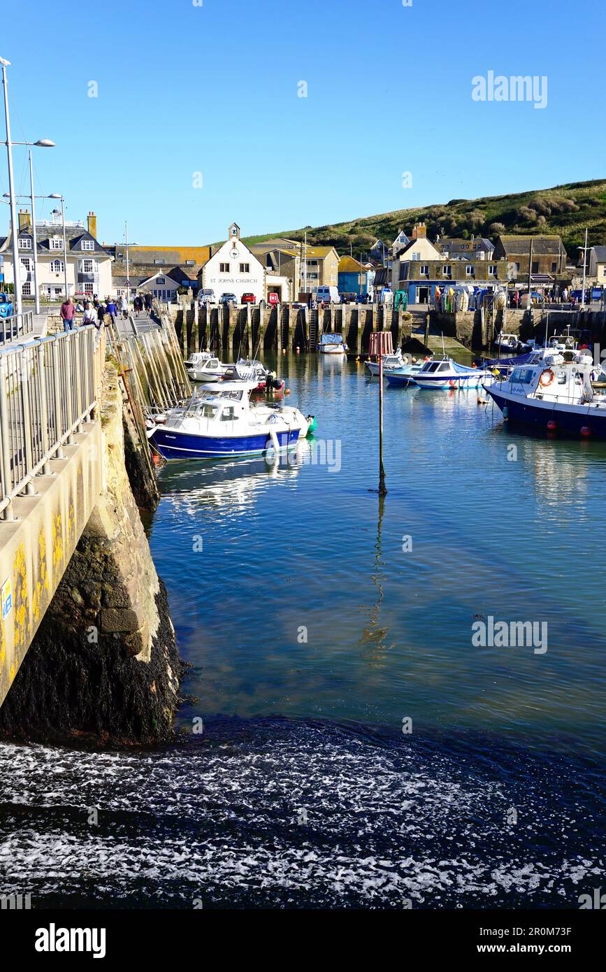 Fishing boats moored in the harbour with town buildings to the rear and the sluice gate to the left, West Bay, Dorset, UK. Stock Photo