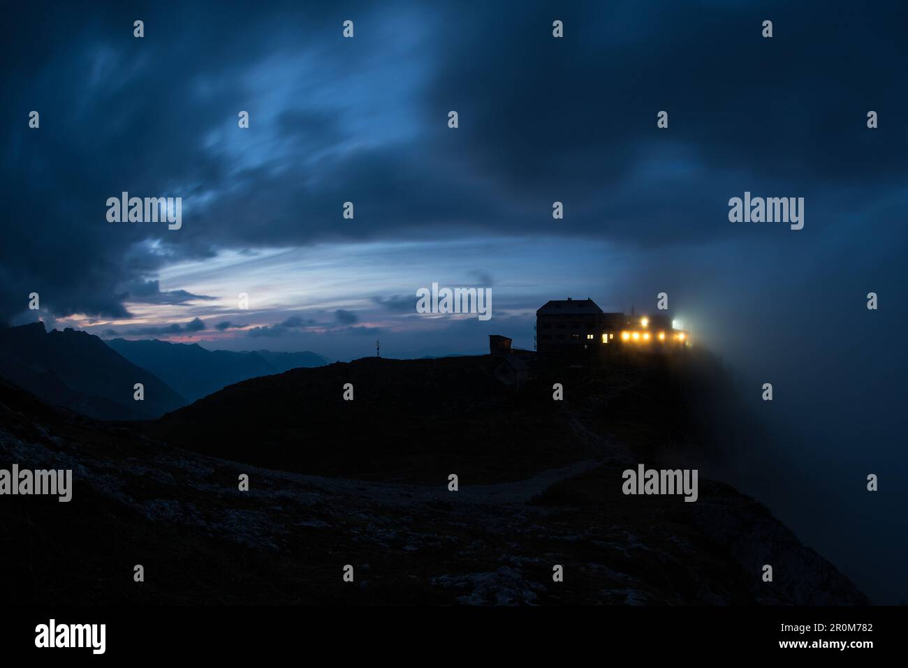 Brightly lit windows of the Watzmannhaus at dusk, Berchtesgaden Alps, Berchtesgaden, Germany Stock Photo