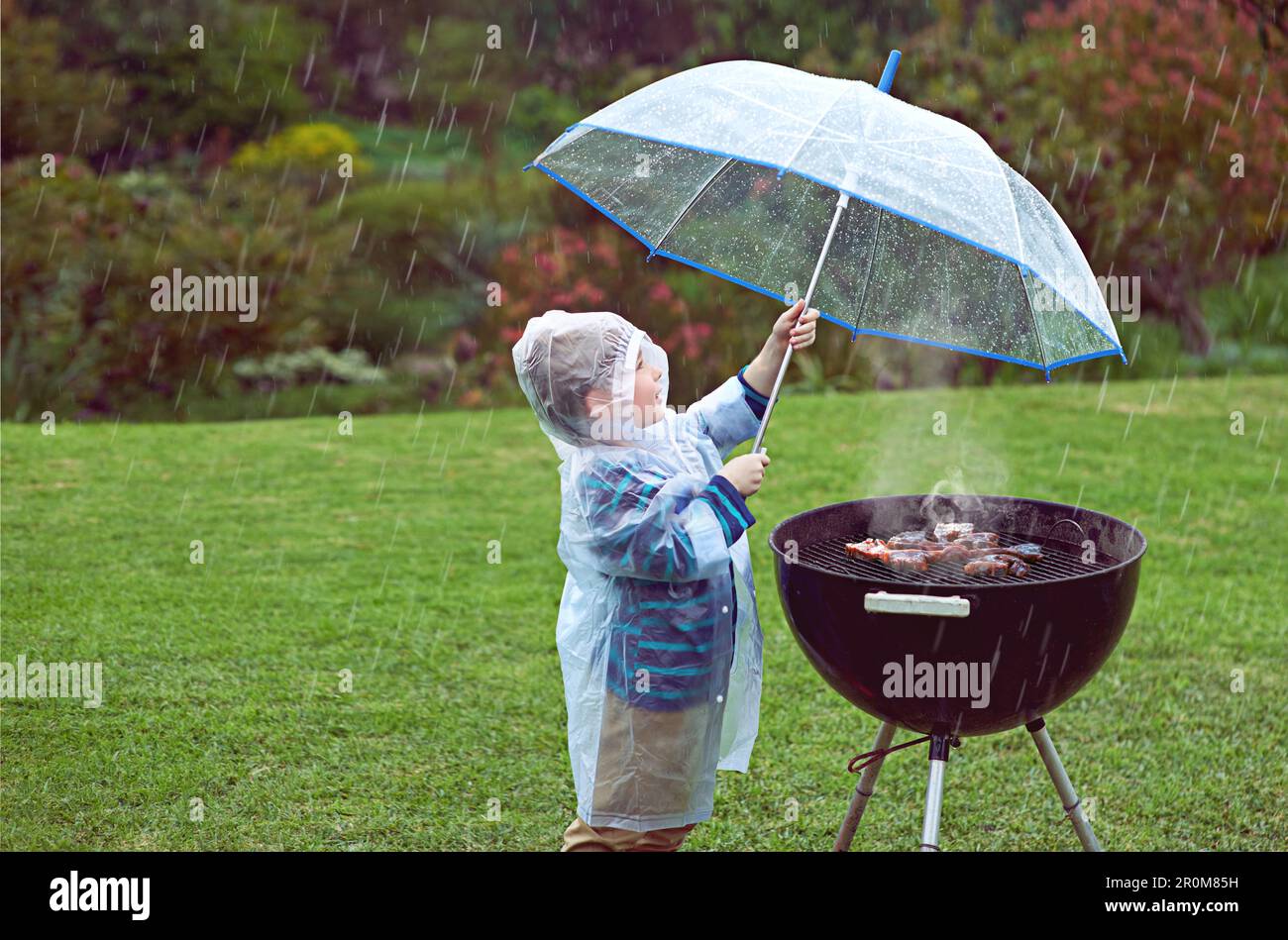 Weather, nature and boy with a grill, rain and wellness with safety, cover  and winter outfit. Bbq, male child or kid with umbrella, cold or young  Stock Photo - Alamy