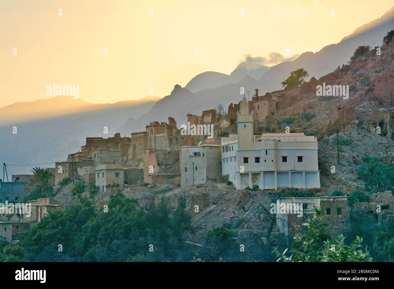 The village Oumesnat shortly after sunset at the foot of steep mountains, Valley of Ammeln in Anti Atlas, Morocco Stock Photo