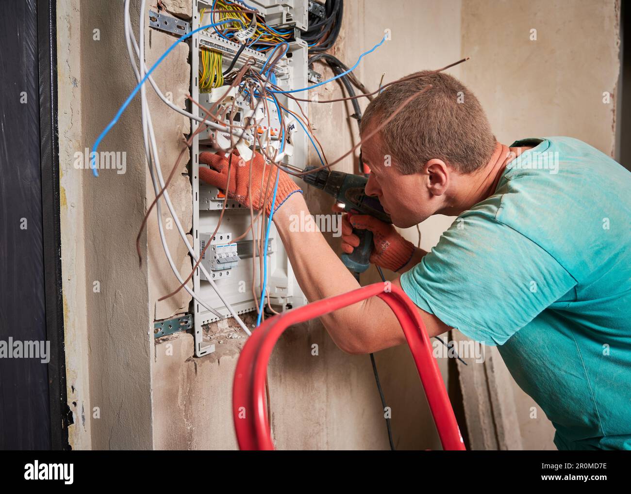 Side view of man in work gloves fixing electrical switchboard with