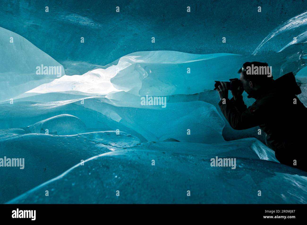 Adventure Photographer in blue ice cave in the Swiss Alps Stock Photo