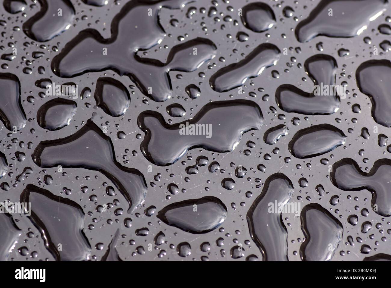 Close up of the texture of rainwater, raindrops on a black glass table