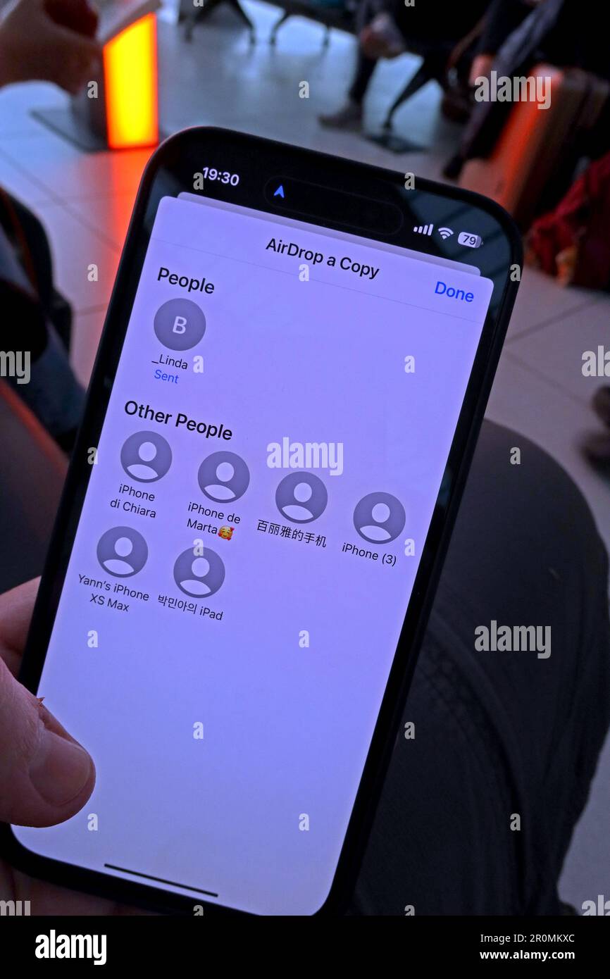 Dangers of sharing an image using AirDrop transfer in a public place, like an airport, to nearby strangers phones. Stock Photo