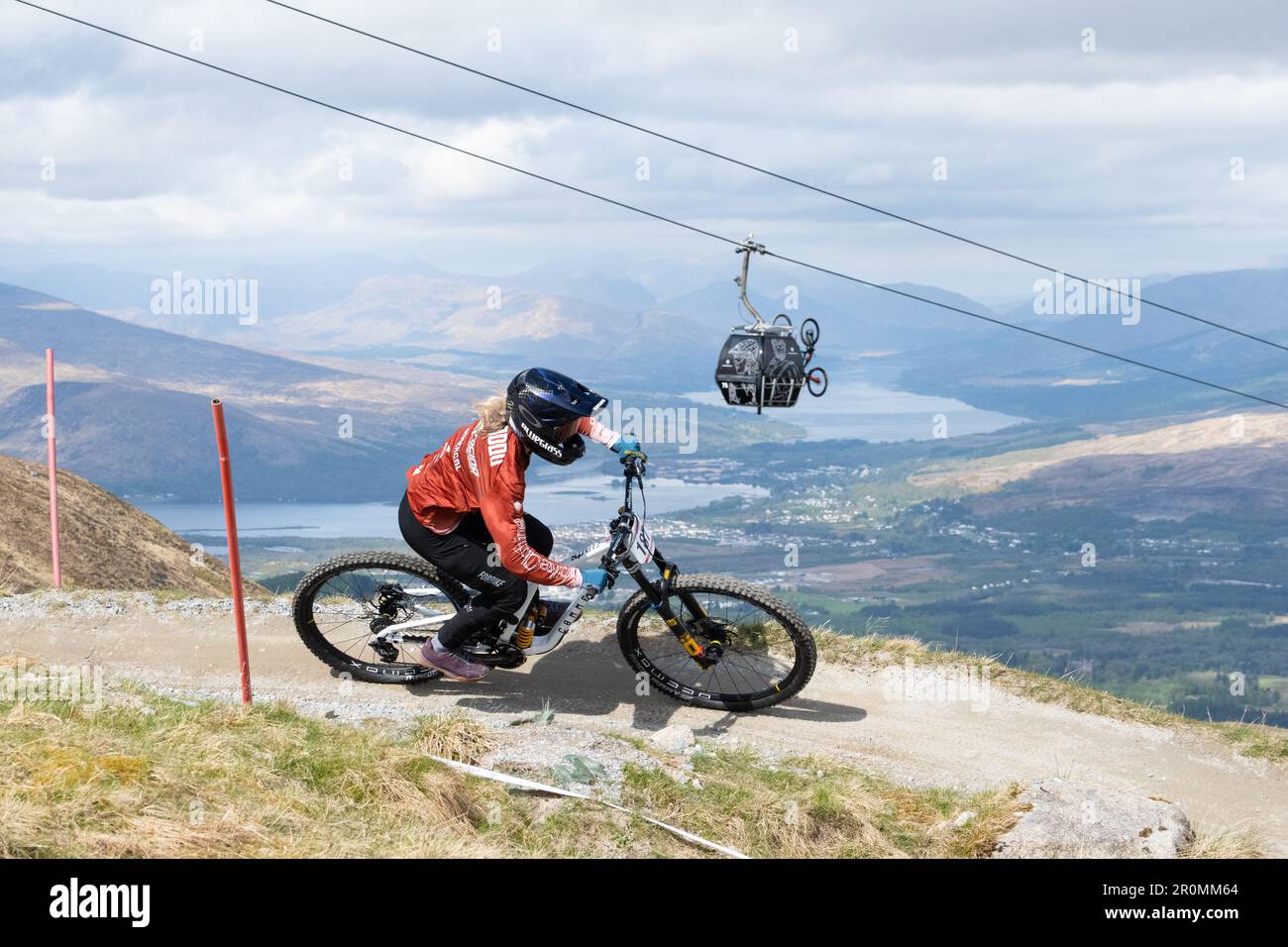 Downhill Mountain biker riding at the Nevis Range Mountain Resort with view of the Great Glen and Fort William behind, Fort William, Scotland, UK Stock Photo