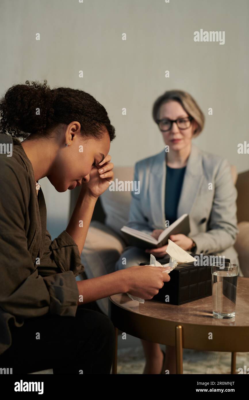 Young depressed female patient touching head during psychological ...