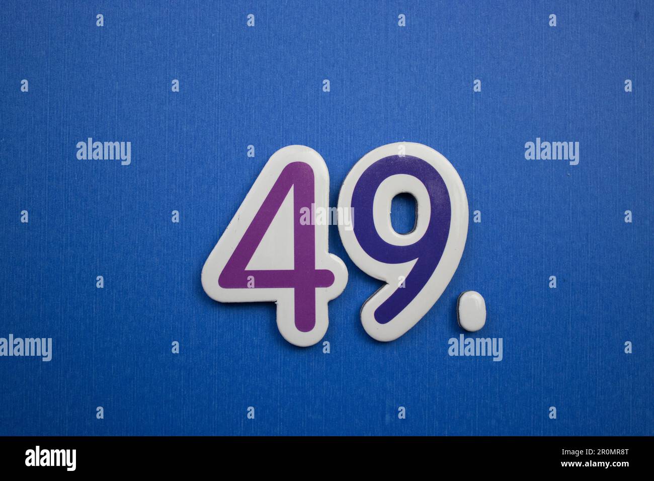 The number 49, placed on a blue background, photographed from above, colored purple and dark blue. Stock Photo