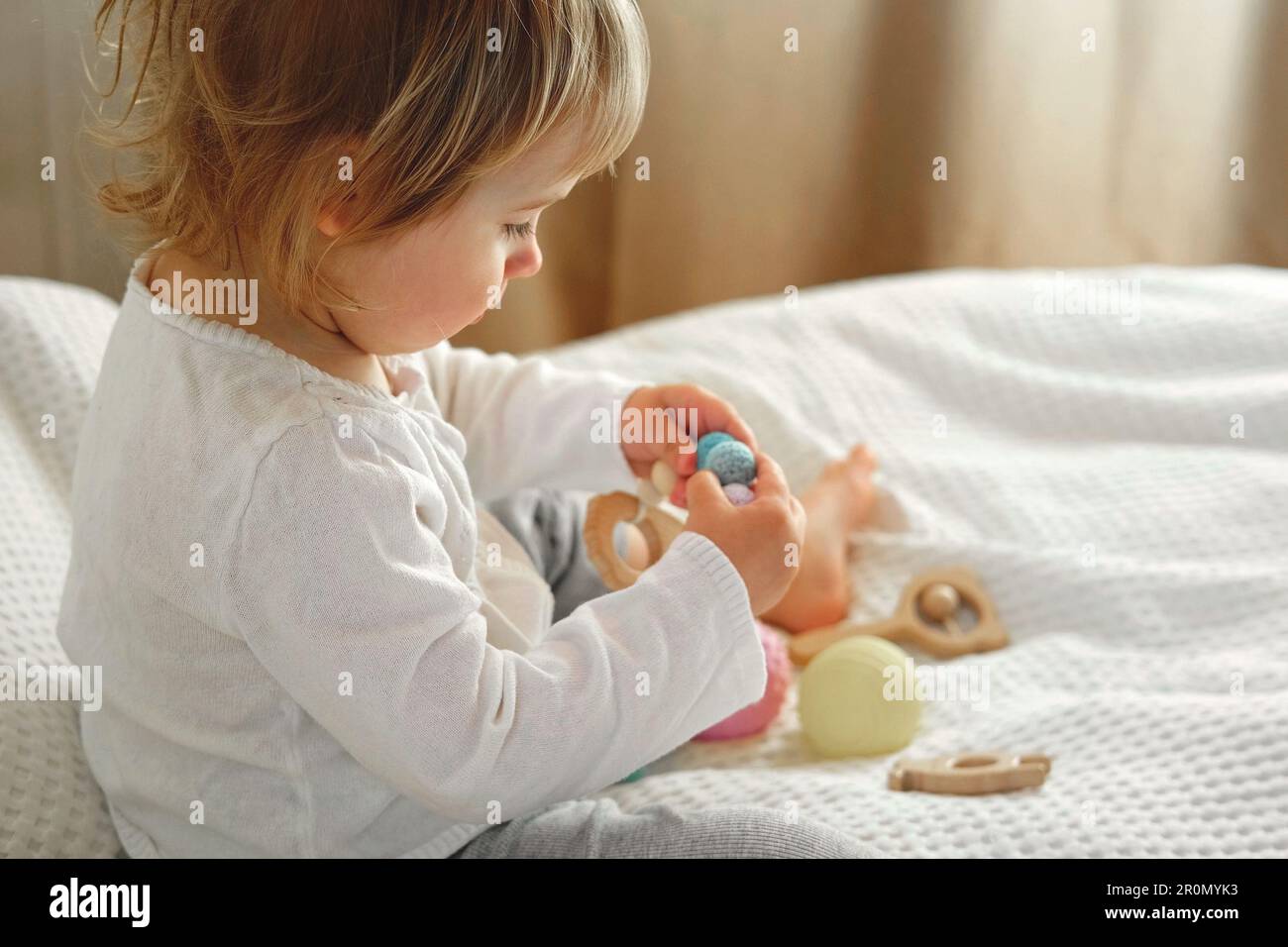 Cute baby girl playing tactile wooden and silicone toys. Young child ...