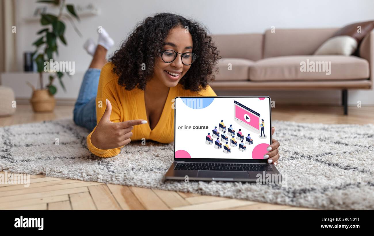 Happy young black woman lying on floor, pointing at laptop Stock Photo ...