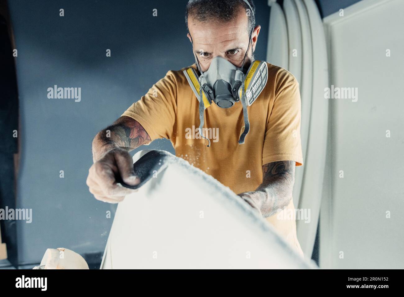 Serious focused adult bearded male master with respirator on mask ...