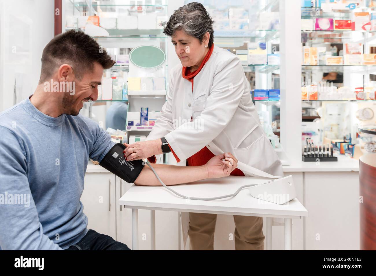 Concentrated female pharmacist in white robe using sphygmomanometer