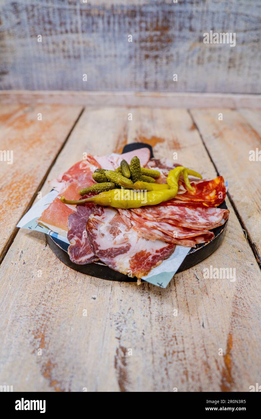 A platter filled with assorted cured meats and pickled vegetables. Stock Photo