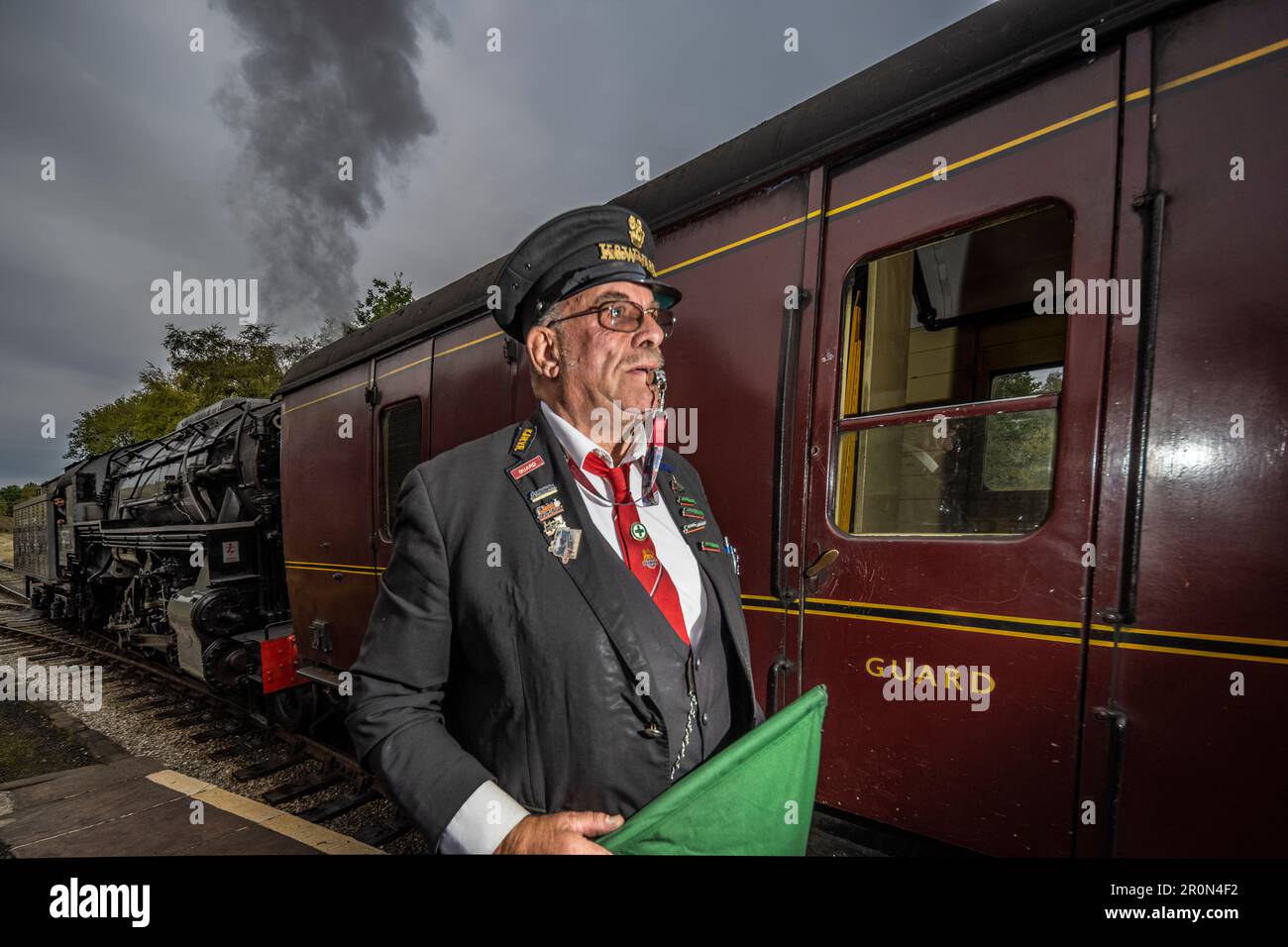 Train guard signalling the departure of historic train on the Keighley