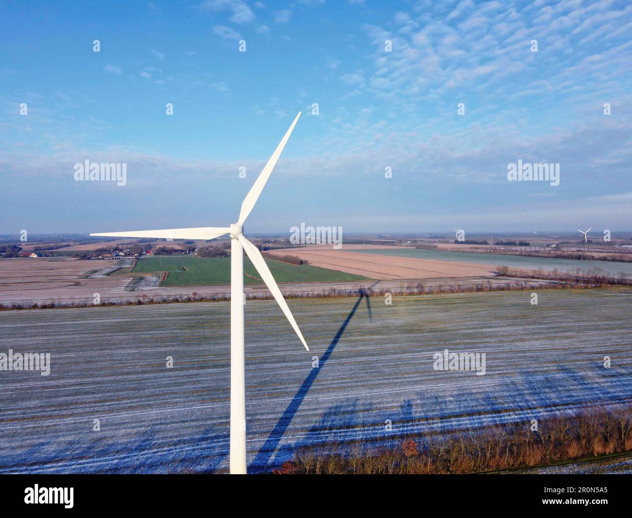 A lone wind turbine stands against the backdrop of a barren wintery ...