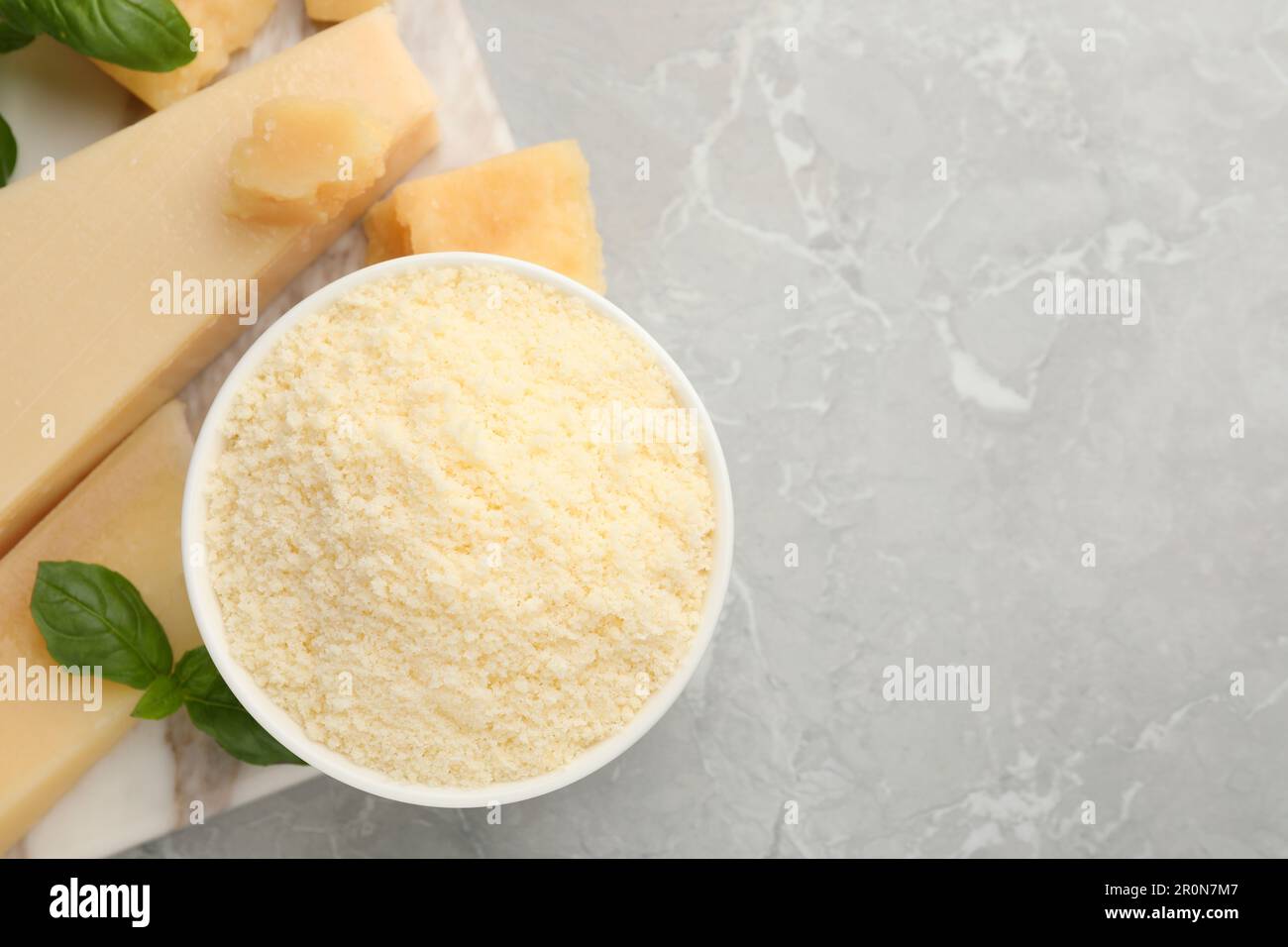 Flat lay composition with parmesan cheese and basil on grey table ...